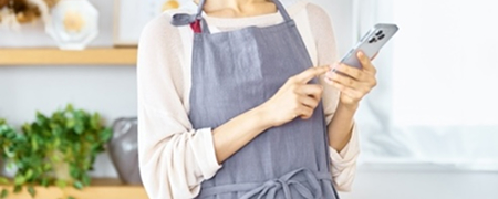 エプロンをした女性がスマホを操作している様子